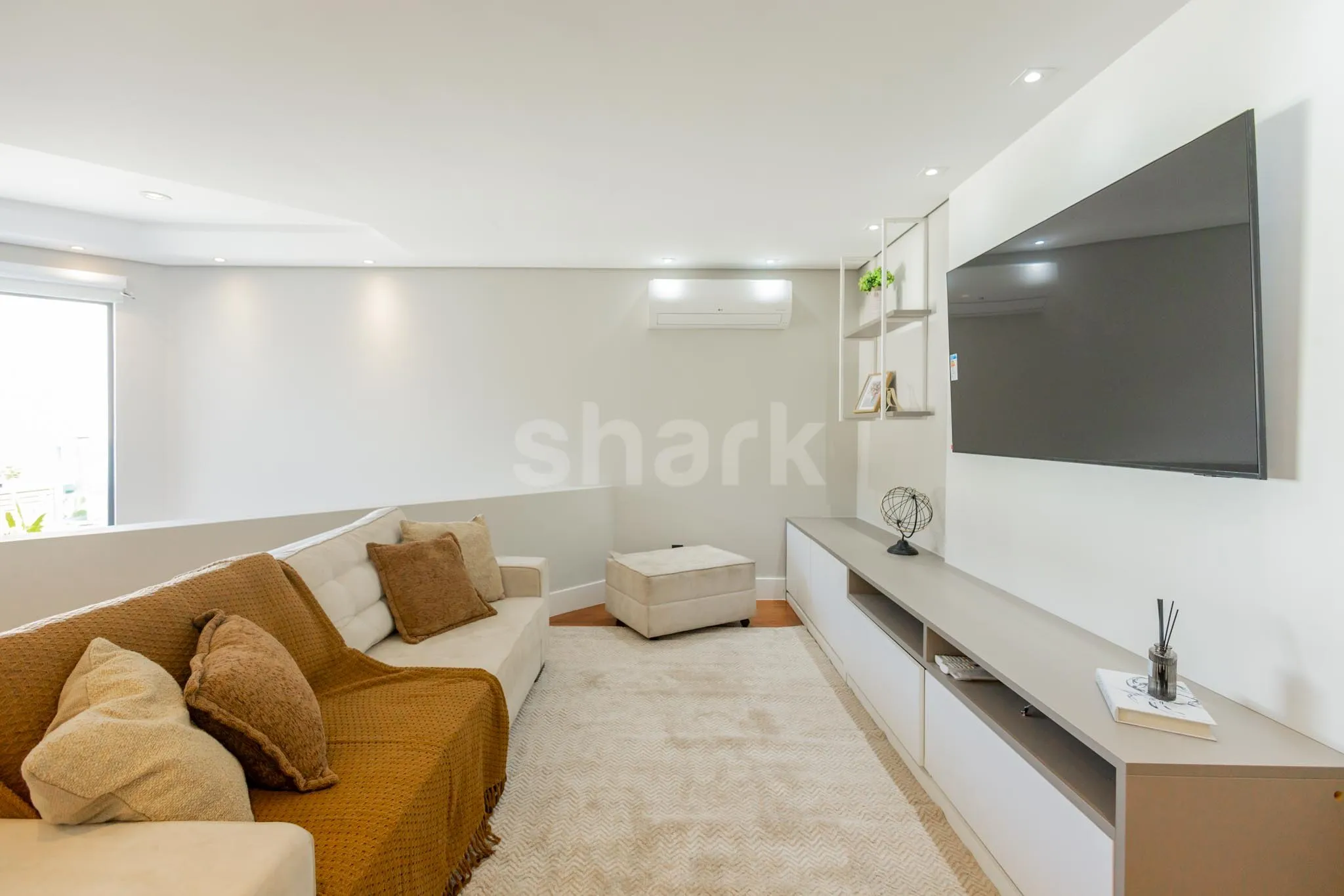 Sala de TV com sofá e painel de televisão