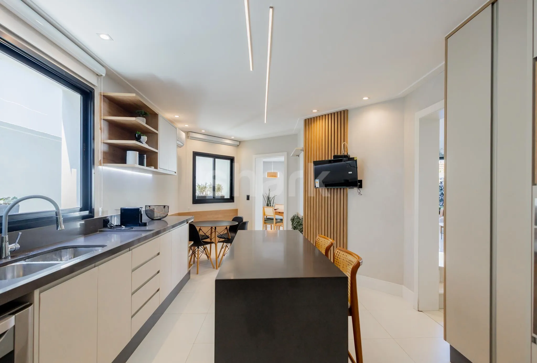 Cozinha com ilha, mesa de refeições e painel ripado
