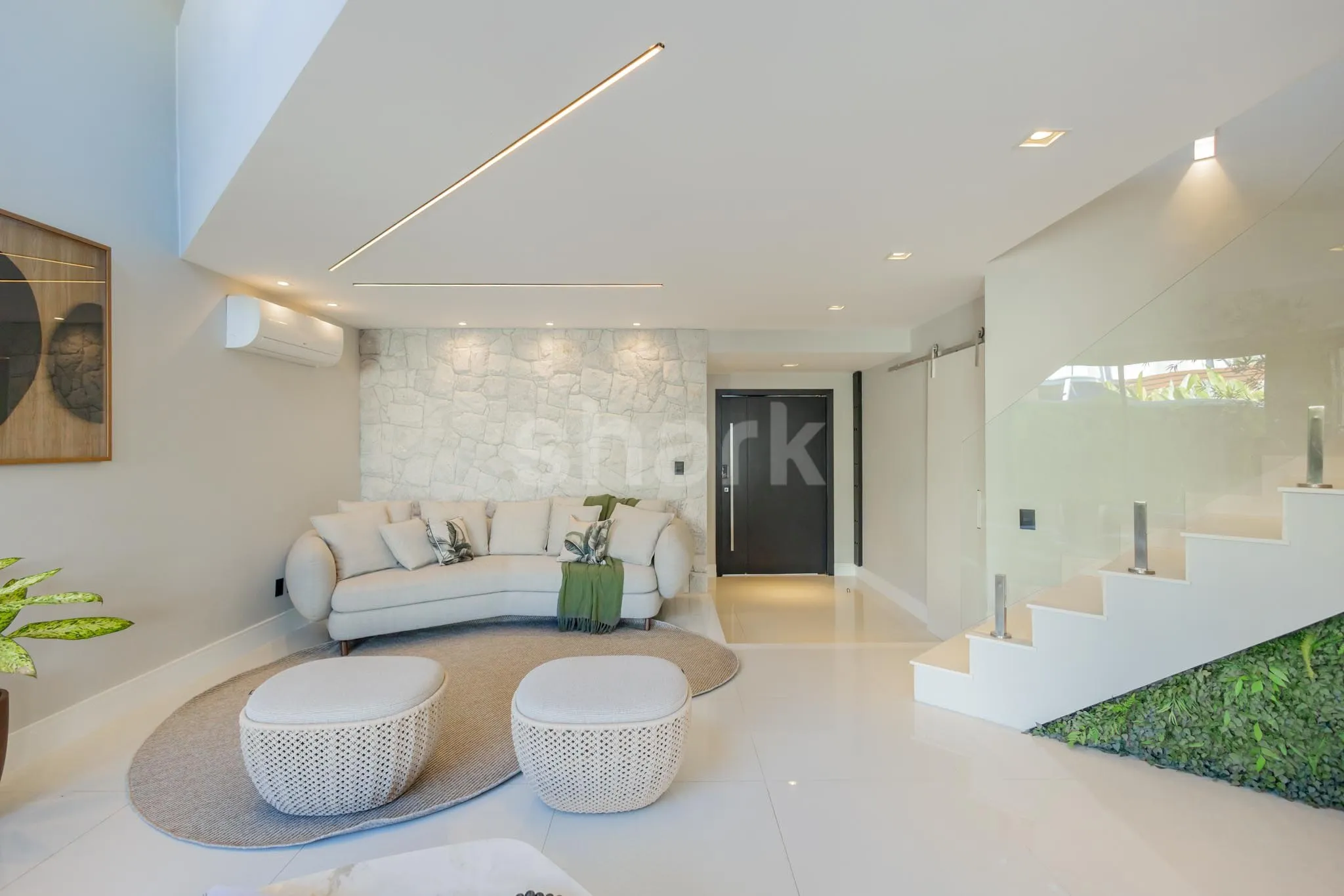 Hall de entrada com parede de pedra e porta pivotante escura